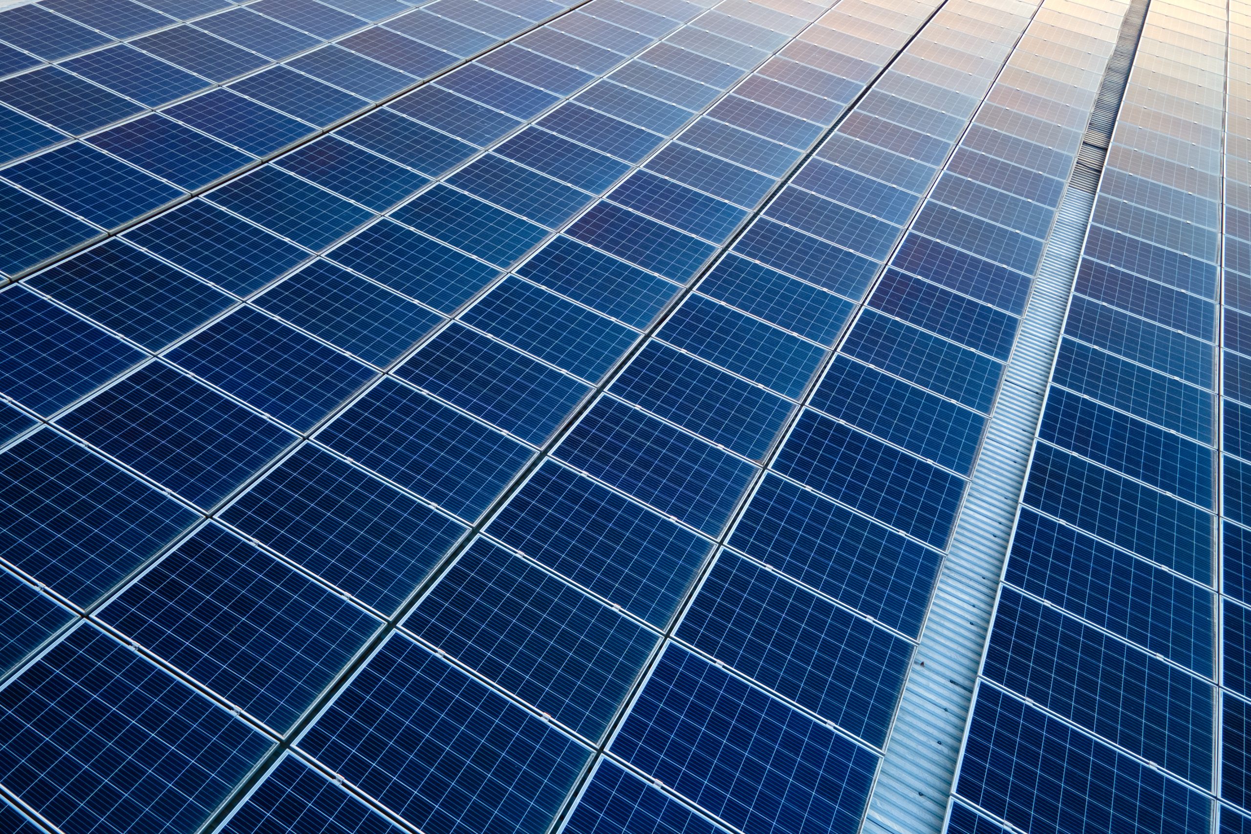 Blue photovoltaic solar panels mounted on building roof for producing clean ecological electricity at sunset. Production of renewable energy concept.