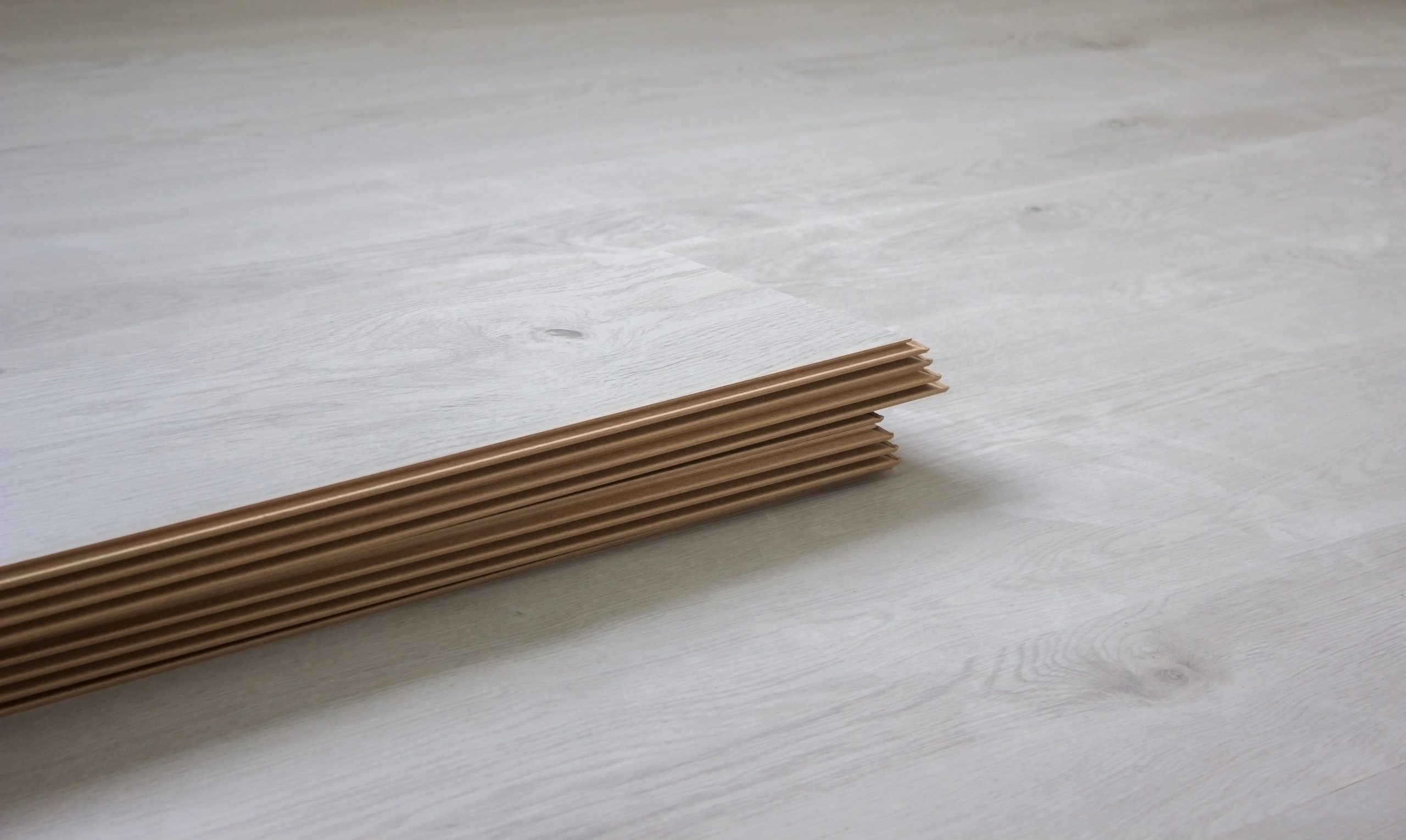 Workers' hands install a wooden laminate floor.